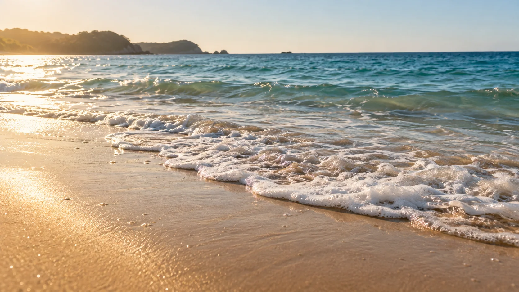 Gentle sea foam washing over golden sand.